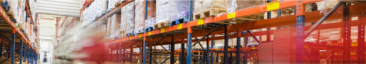 Foto: eine Lagerhalle mit hohen Regalen. Mittig f&auml;hrt ein Gabelstapler.