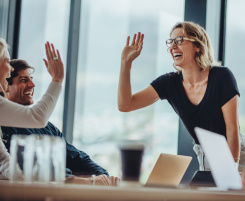 Foto: eine l&auml;chelnde Ausbilderin oder Lehrerin hat die Hand in der Luft um der Kollegin ein High-Five zu geben. 