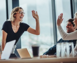 Foto: eine l&auml;chelnde Ausbilderin oder Lehrerin hat die Hand in der Luft um der Kollegin ein High-Five zu geben. 